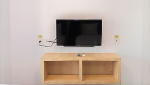 A flat-screen TV mounted on a white wall with a wooden console below.
