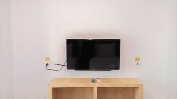 A flat-screen TV mounted on a white wall with a wooden console below.