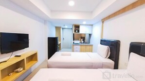 A hotel room with two beds, a TV, a desk, and a kitchenette. - Comfort Studio At De Prima Apartment (Medan)