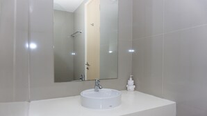 A bathroom with a white sink, a mirror, and a hand soap dispenser. - Cozy Living Studio Apartment Tree Park City Bsd (South Tangerang)