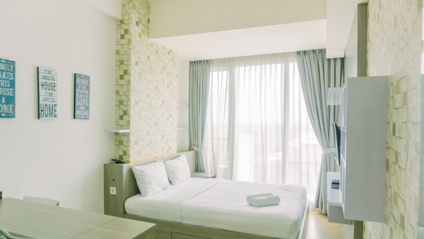 A modern hotel room with a large bed, a desk, and a TV. - Cozy Living Studio Apartment Tree Park City Bsd (South Tangerang)