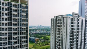 Ein Hochhaus mit einer Fenster- und Balkongitterung, das auf einen Fluss und einen Park mit Bäumen und einem kleinen Gebäude blickt.