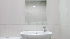 A bathroom with a white sink, a mirror above it, and a toilet to the left.