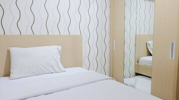 Una cama bien tendida con sábanas blancas, cabecera de madera y pared con un estampado ondulado.