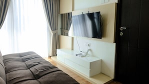 A modern hotel room with a large bed, a white console table, a flat-screen TV mounted on the wall, and a dark door.