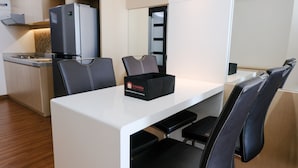 A modern kitchen with a refrigerator, a dining table with chairs, and a bench.