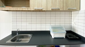 Una cocina con encimera negra, pileta de acero inoxidable y alacenas de madera.