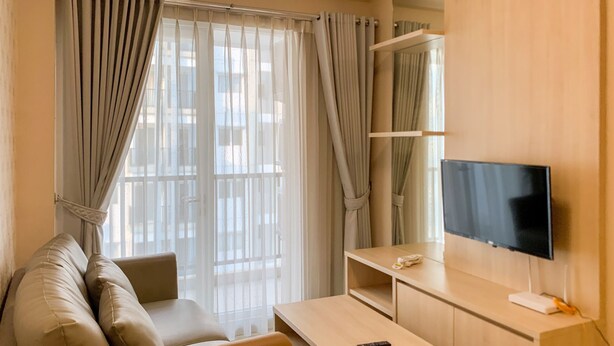 Ein modernes Wohnzimmer mit einer Couch, einem Couchtisch, einem Fernseher und einem Balkon mit Vorhängen.
