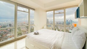 A modern bedroom with a large bed, two windows, and a city view. - Spacious And Comfort Living 2Br At Menteng Park Apartment (Jakarta)