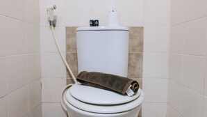 A toilet with a towel on the seat and a toilet paper holder above it.