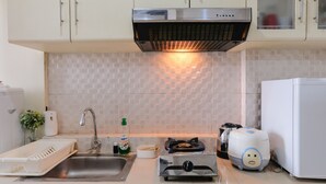 A kitchen with a stainless steel range hood, a sink, a stove, a toaster, and a refrigerator.