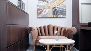 A modern living room with a brown sofa, a round coffee table, and a wall-mounted abstract painting.