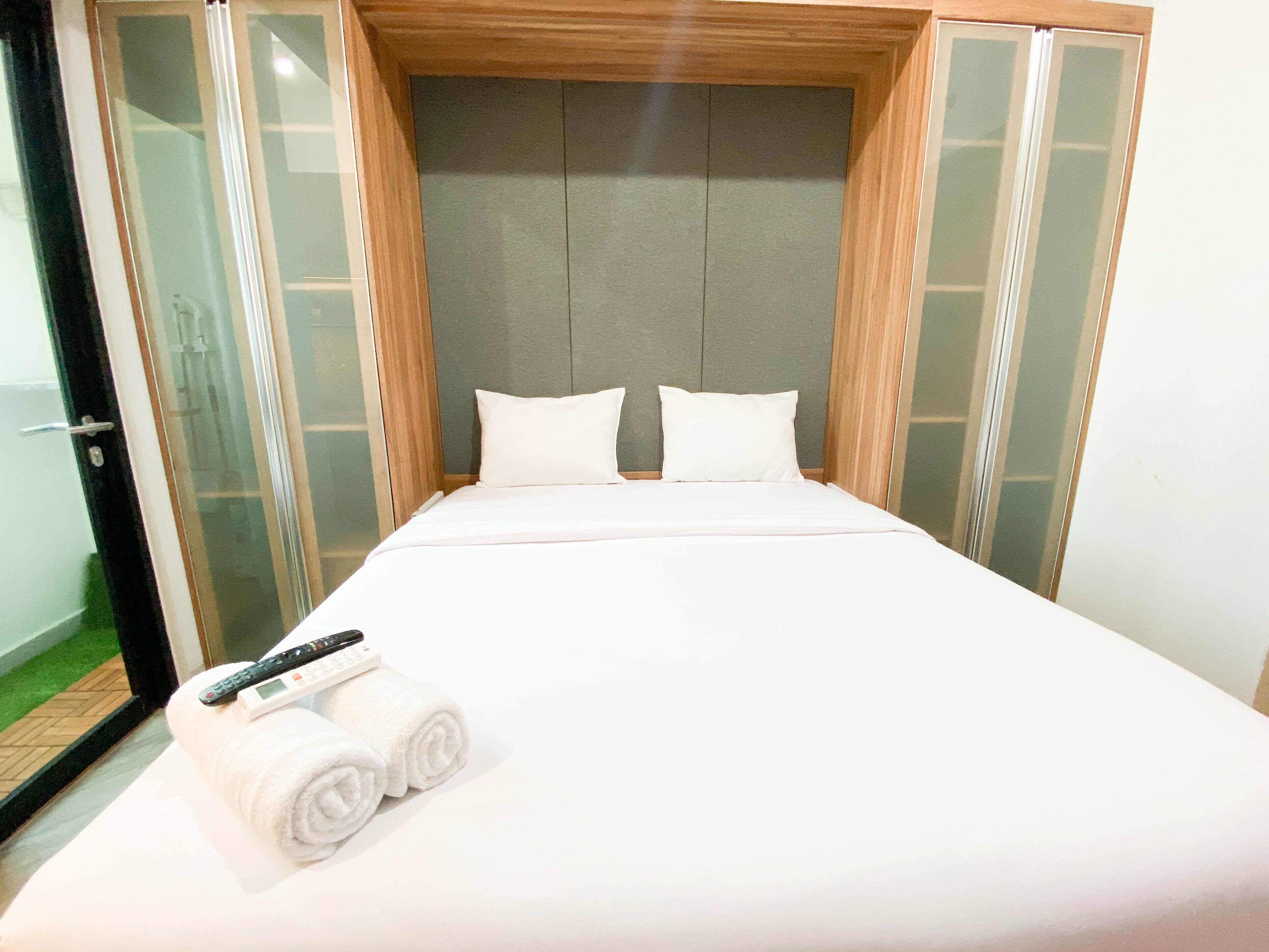 Ein Hotelzimmer mit einem großen Bett, einem Holzkopfende und einer Glastür.