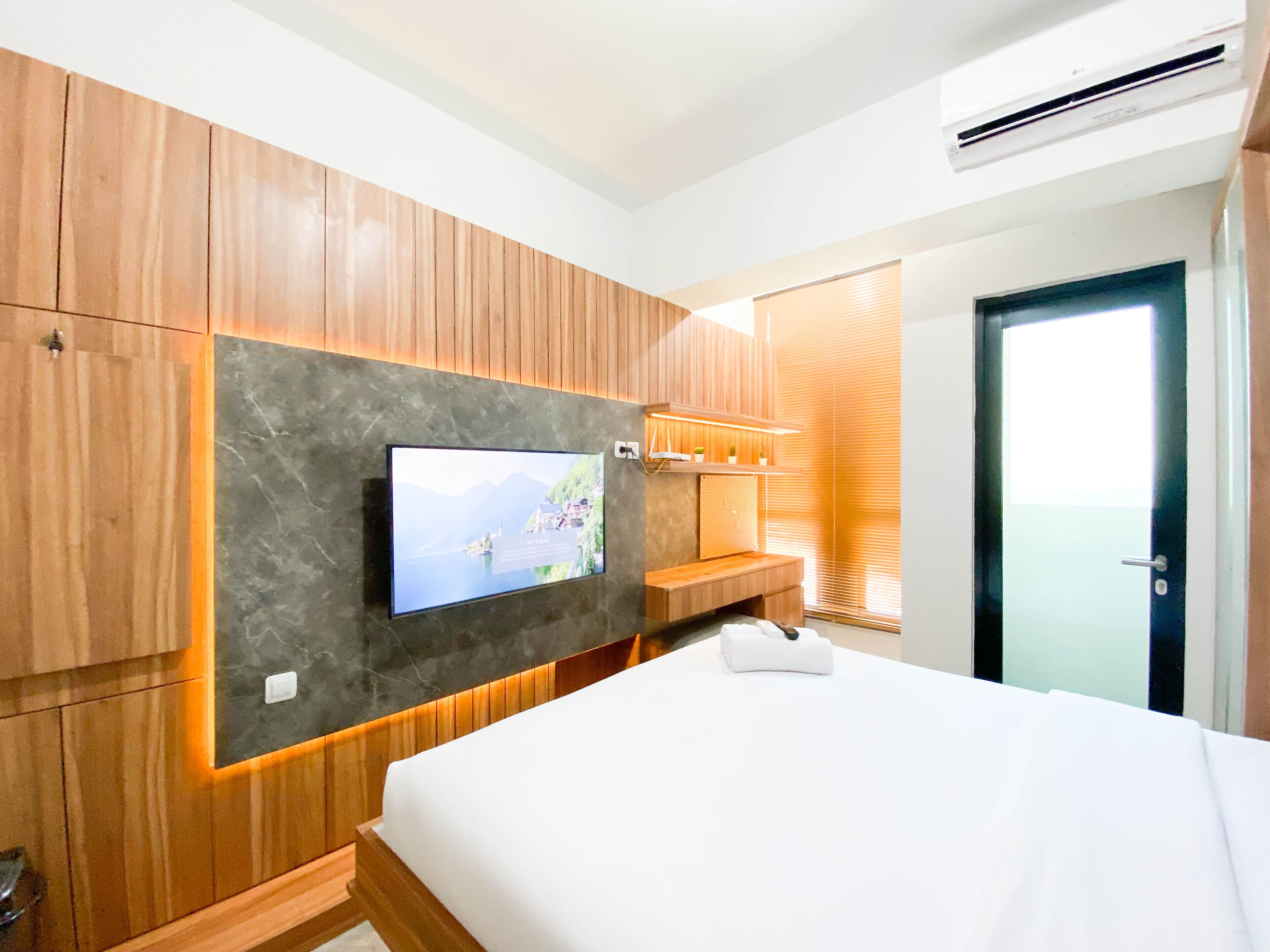 Une chambre d’hôtel moderne dotée d’un grand lit, de lambris en bois, d’un téléviseur à écran plat et d’une banquette intégrée.