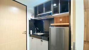 Una cocina compacta con microondas integrado, refrigerador de acero inoxidable y un lavamanos.