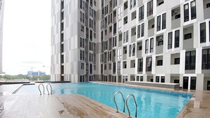 Un edificio moderno con piscina, varios balcones y vista a la ciudad.