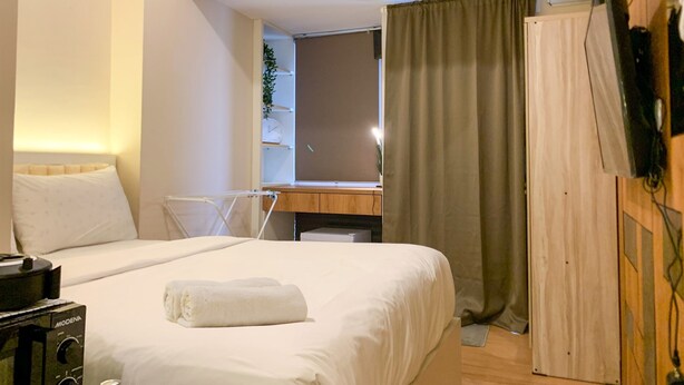 Ett hotellrum med en säng, ett skrivbord, en stol och en tv som är monterad på väggen.