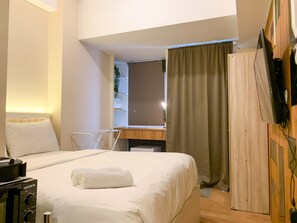 A hotel room with a bed, a desk, a chair, and a TV mounted on the wall. - Minimalist And Nice Studio At Tokyo Riverside Pik 2 Apartment (Teluknaga)