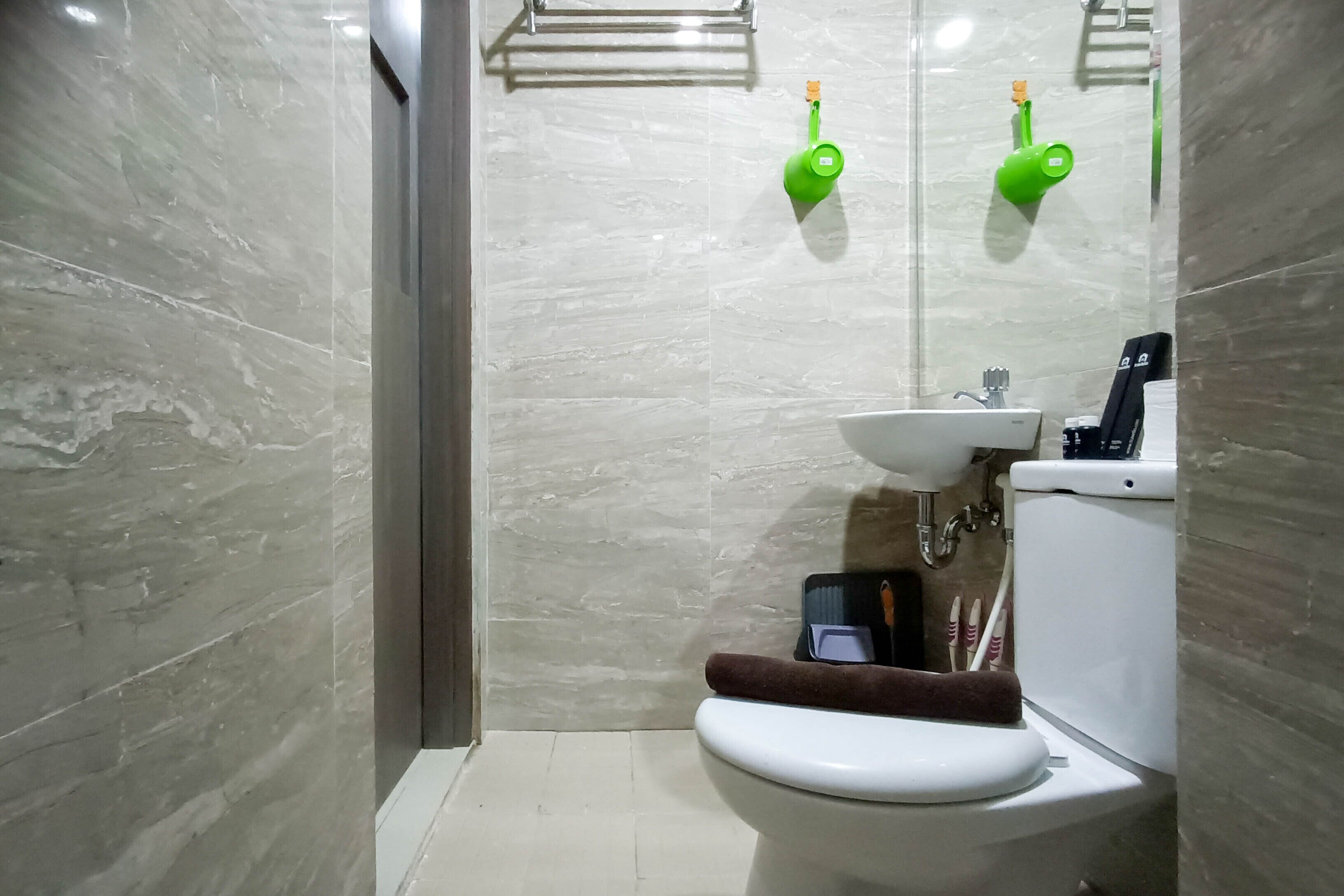 A modern bathroom with a toilet, sink, and green wall-mounted showerheads.