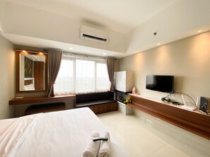 Quarto de hotel com cama, área de estar, televisão e minibar.