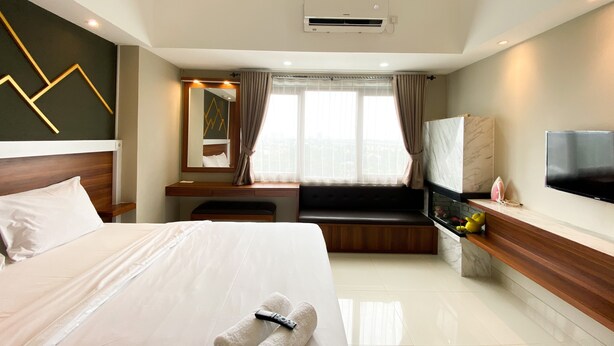A modern hotel room with a large bed, a seating area, a flat-screen TV, and a city view.