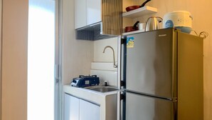 A compact kitchen with a built-in gas stove, a stainless steel refrigerator, and a small sink. - Nice Designed And Elegant 2Br At Green Bay Pluit Apartment (Jakarta)