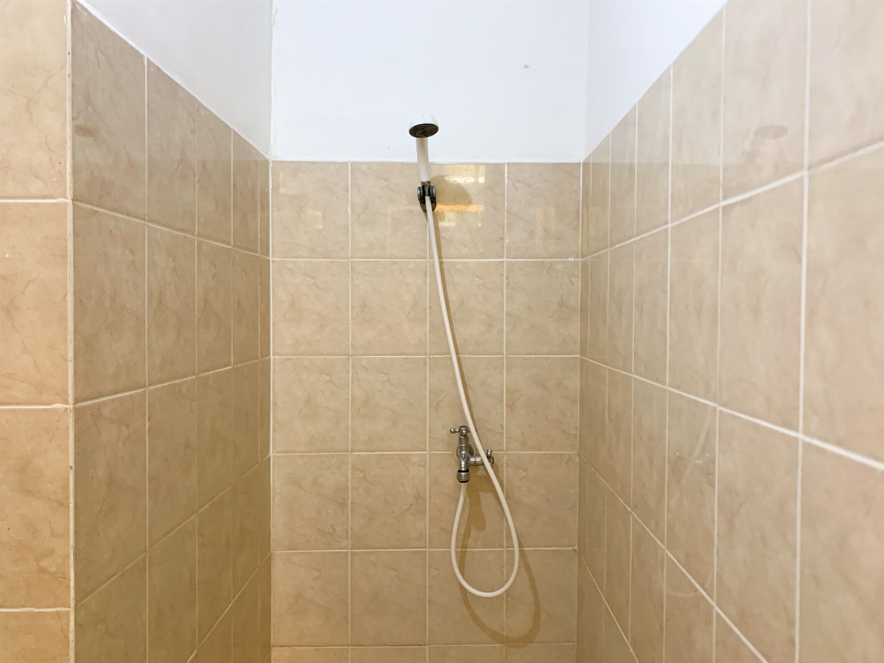 A shower with beige tiles and a white ceiling.