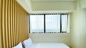 Une chambre d’hôtel avec un lit, une fenêtre avec des stores et une vue sur le paysage urbain.