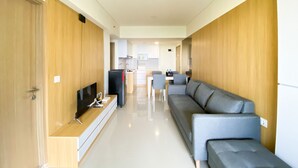 Un salon moderne avec un canapé gris, un téléviseur à écran plat et un meuble en bois.