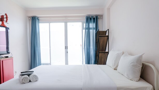 Una habitación de hotel con una cama, un escritorio con computadora y un ventanal con cortinas.
