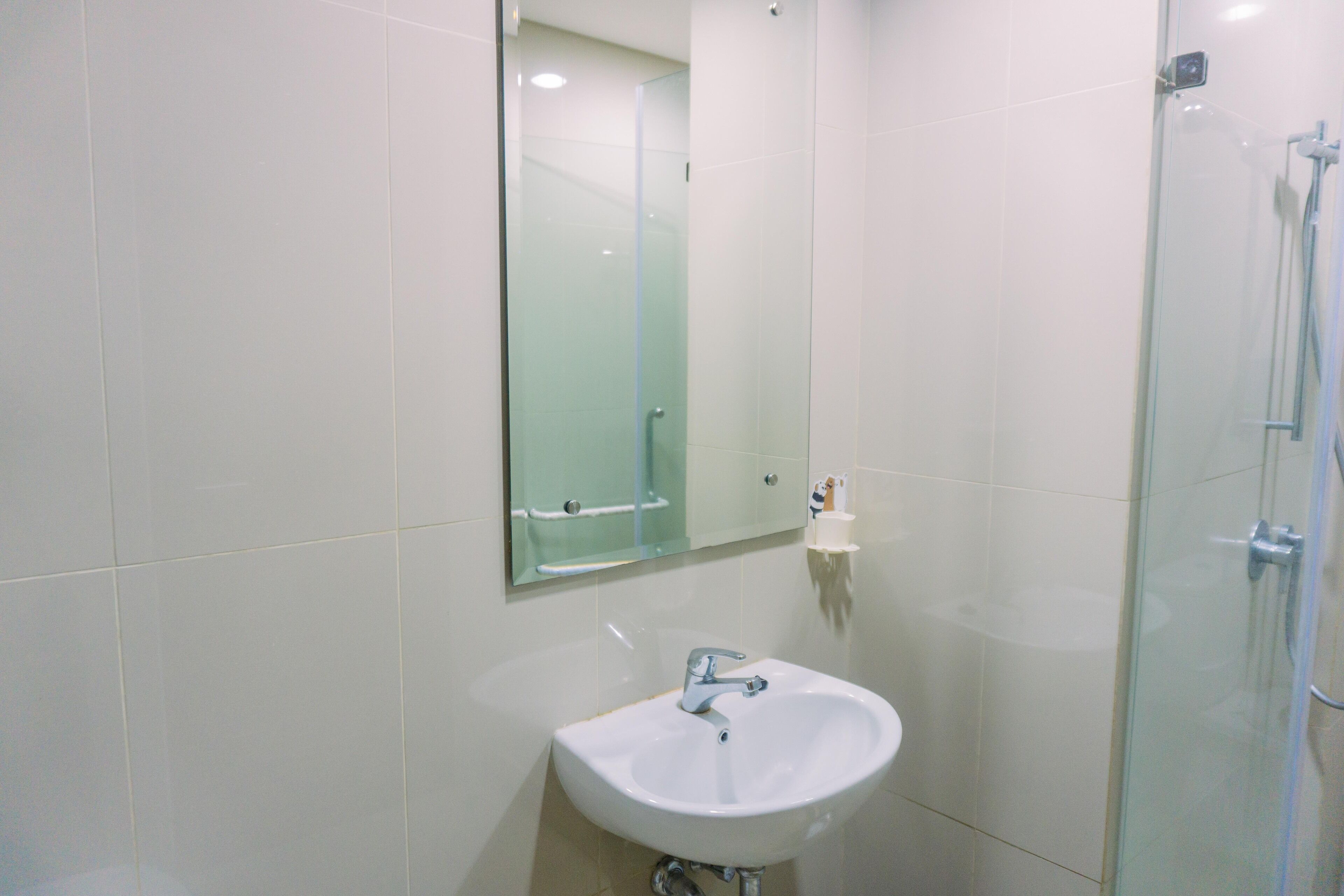 A bathroom with a white sink, a glass shower enclosure, and a mirror above the sink.
