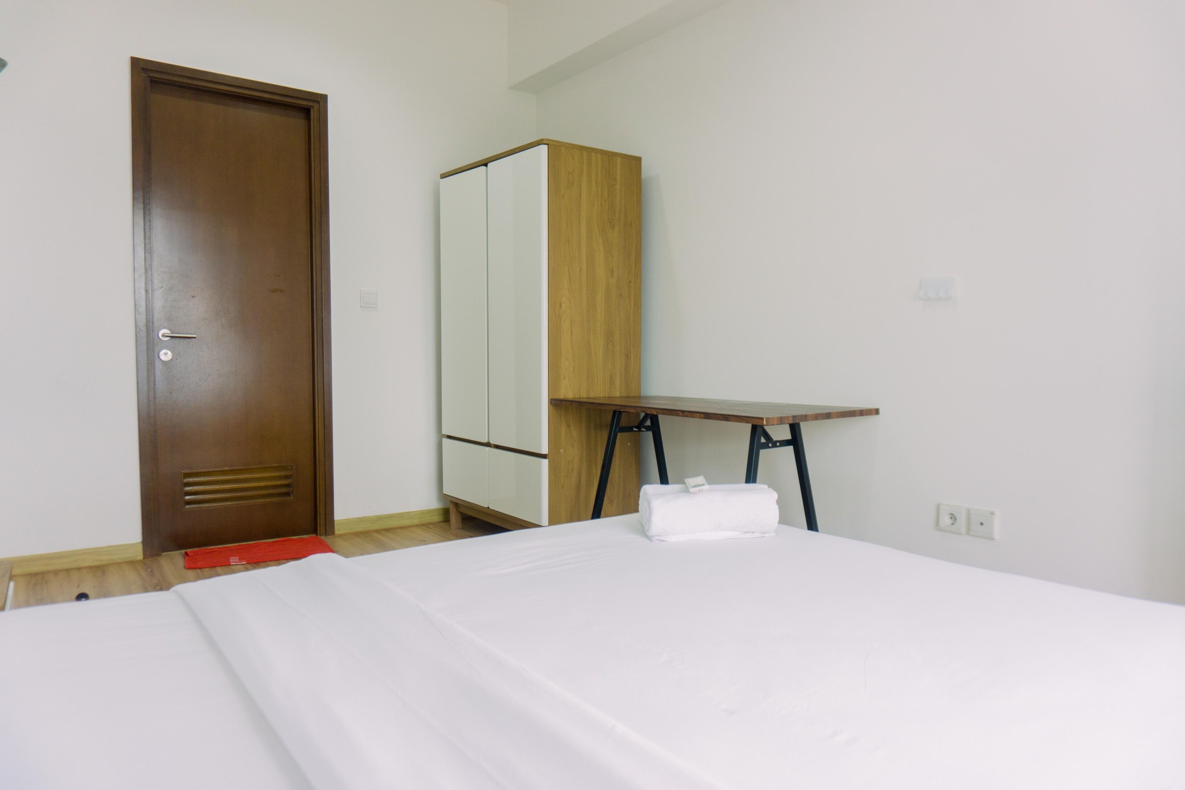 Una habitación de hotel con cama, armario de madera, escritorio y puerta.
