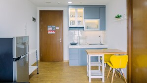 A compact kitchen with a refrigerator, a sink, and a dining area with a table and two chairs. - Cozy Stay 1Br At M-Town Signature Apartment (Gading Serpong)