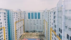 A high-rise residential building with multiple floors, a central courtyard, and a basketball court. - Fancy And Nice 1Br At Paramount Skyline Apartment (Gading Serpong)