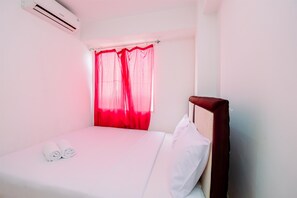A hotel room with a bed, white linens, a red curtain, and a white pillow. - Strategic Designed And Simply 2Br At Bassura City Apartment (Jakarta)