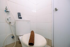 A bathroom with a toilet, a shower hose, and a toilet paper holder. - Strategic Designed And Simply 2Br At Bassura City Apartment (Jakarta)