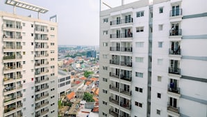 Un edificio residencial alto con varios balcones, ventanas amplias y vistas de la ciudad circundante.