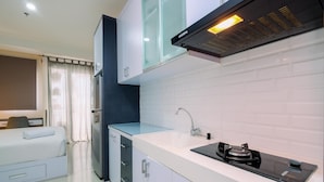 Una cocina moderna con armarios blancos, una estufa integrada y un ventanal con cortinas.