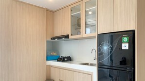 Una cocina moderna con armarios de madera, un lavamanos de acero inoxidable y un refrigerador negro con pantalla digital.