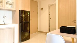 Una cocina con un refrigerador de doble puerta, un lavamanos y una mesa con sillas.