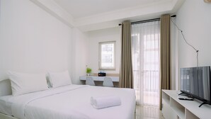 A hotel room with a bed, a desk, a chair, a television, and a window with curtains. - Minimalist And Best Deal Studio Room At Signature Park Grande Apartment (Jakarta)