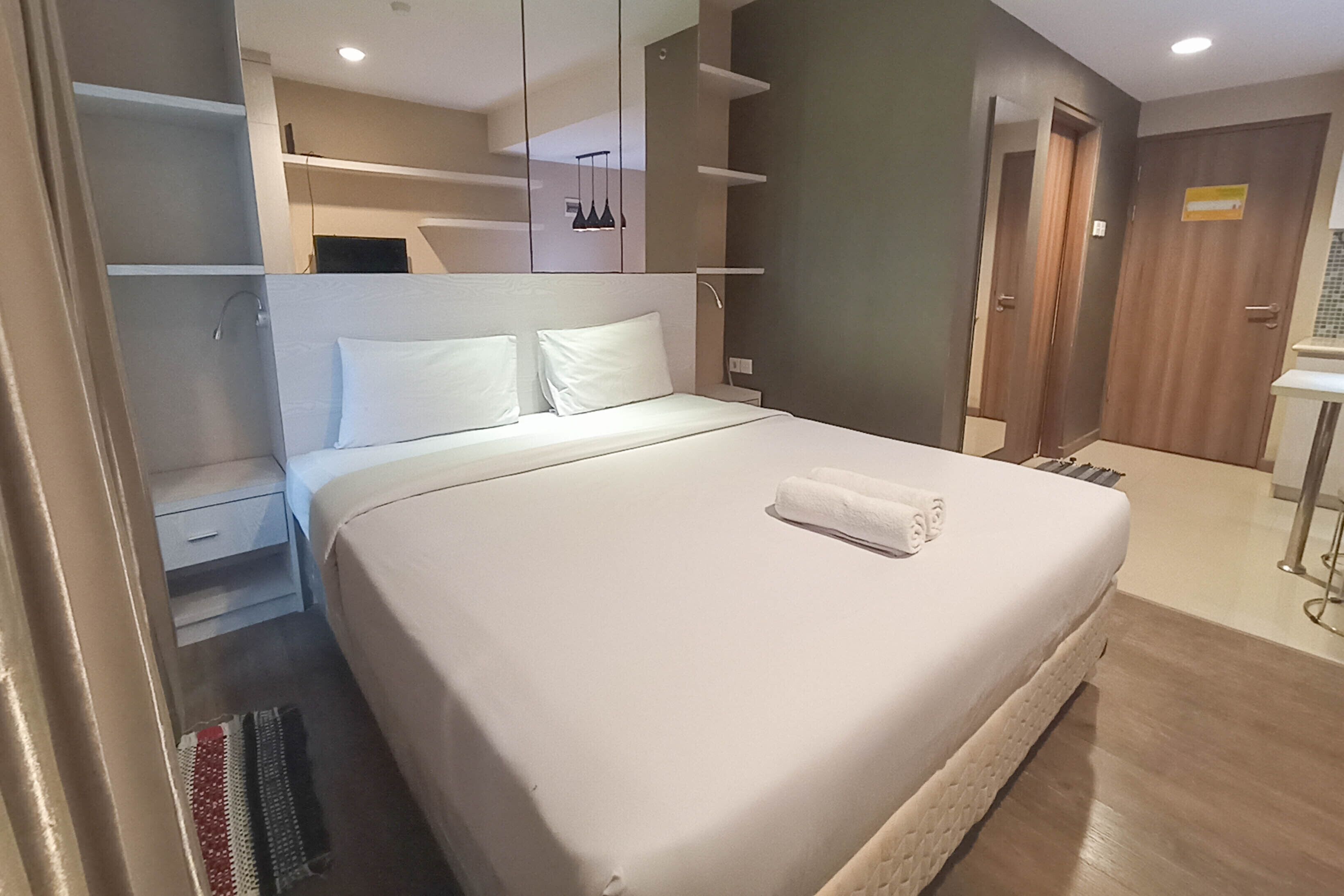 A modern hotel room with a large bed, a walk-in closet, and a bathroom with a shower and toilet.