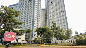 A high-rise building with multiple balconies and a sign indicating a show unit. - Good Deal And Warm Studio Room Casa De Parco Apartment (South Tangerang)