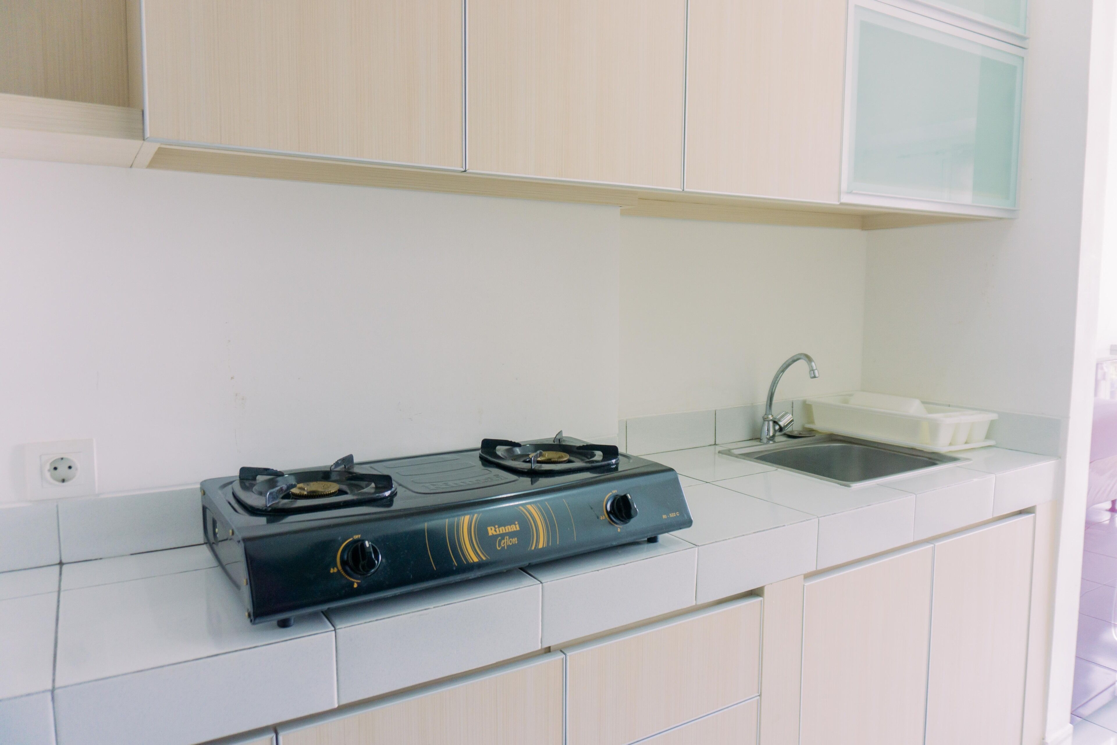 A kitchen with a gas stove, a sink, and white cabinets.