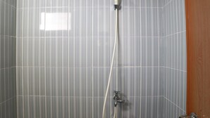 Brusebad med håndbruser og vandhane på væggen.