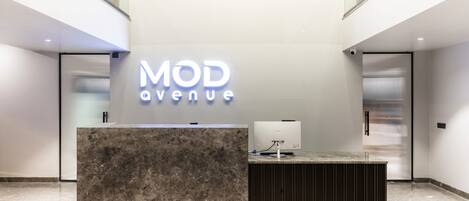 Un mostrador de recepción con encimera de mármol y diseño moderno, que muestra un letrero que dice "MOD Avenue".