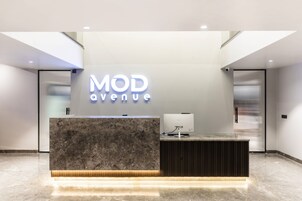 Un mostrador de recepción con encimera de mármol y diseño moderno, que muestra un letrero que dice "MOD Avenue".