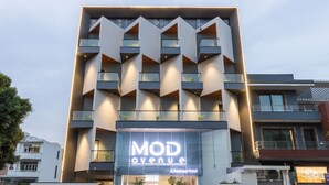 Un hotel moderno con un llamativo letrero que dice 'MOD Avenue Boutique Hotel', que presenta una fachada geométrica con balcones y una entrada central.