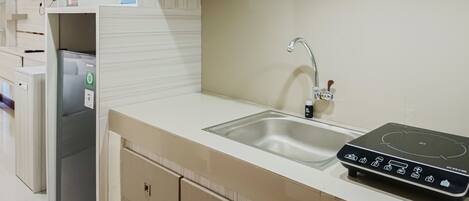 A kitchen with white cabinets, a stainless steel sink, and a black induction cooktop.