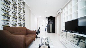 Un salon moderne avec un canapé marron, une table basse en verre, un téléviseur à écran plat et un meuble de rangement blanc.